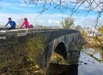 Cyclists crossing stone bridge