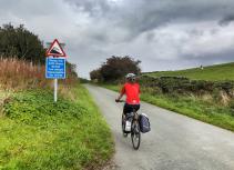Bicyclist on steep hill with warning sign